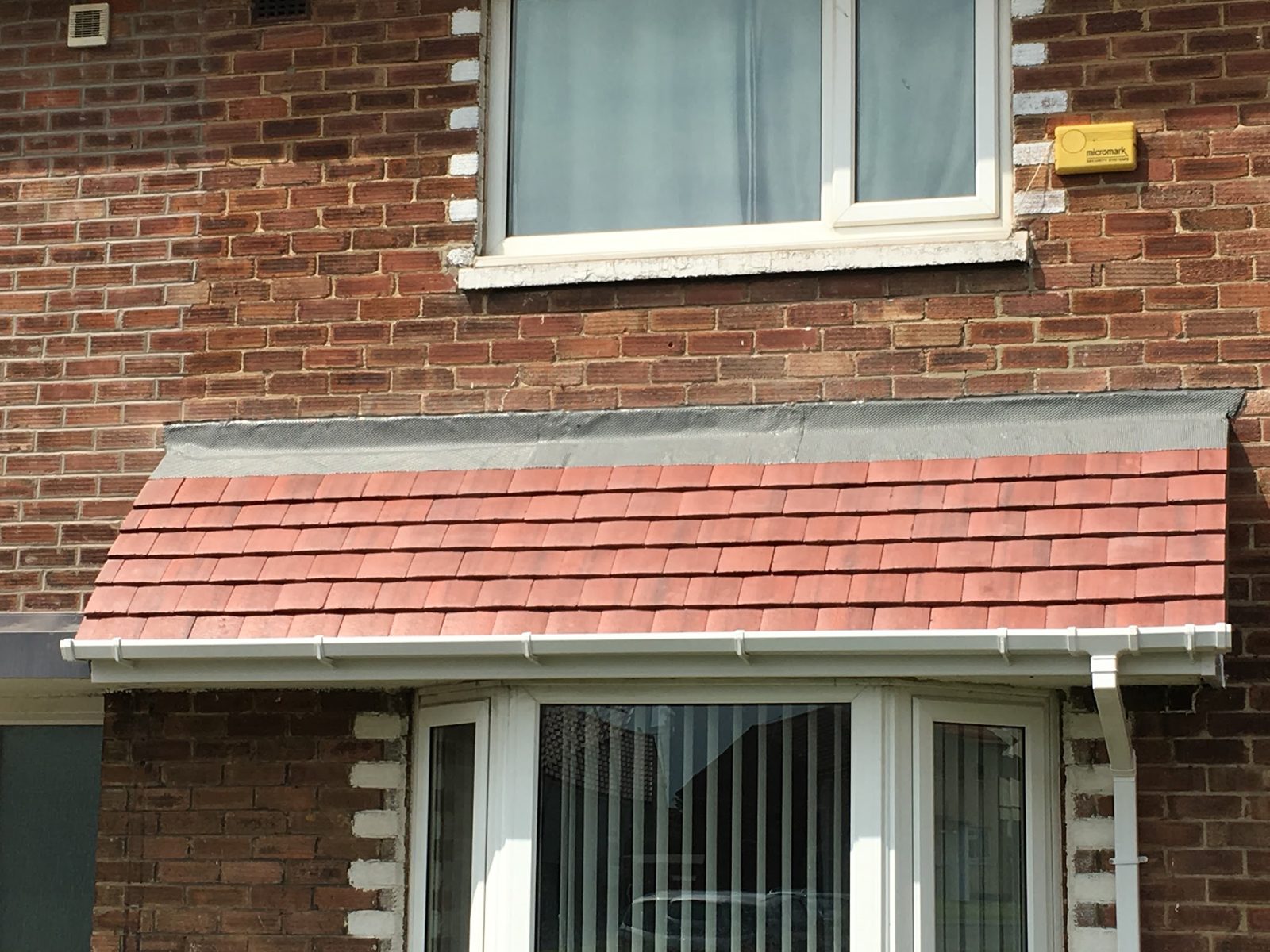 A new red tiled bay window canopy with white fascia and guttering