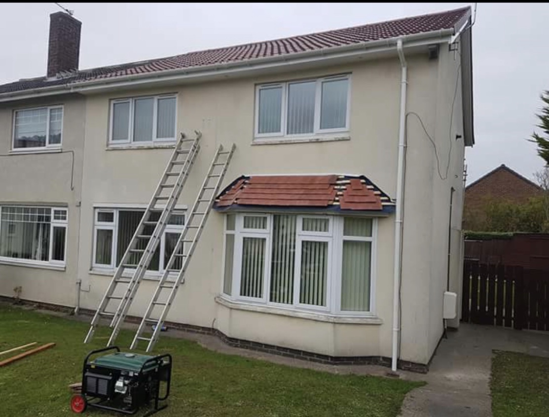 A cream rendered semi with a new tiled bay canopy, ladders still up